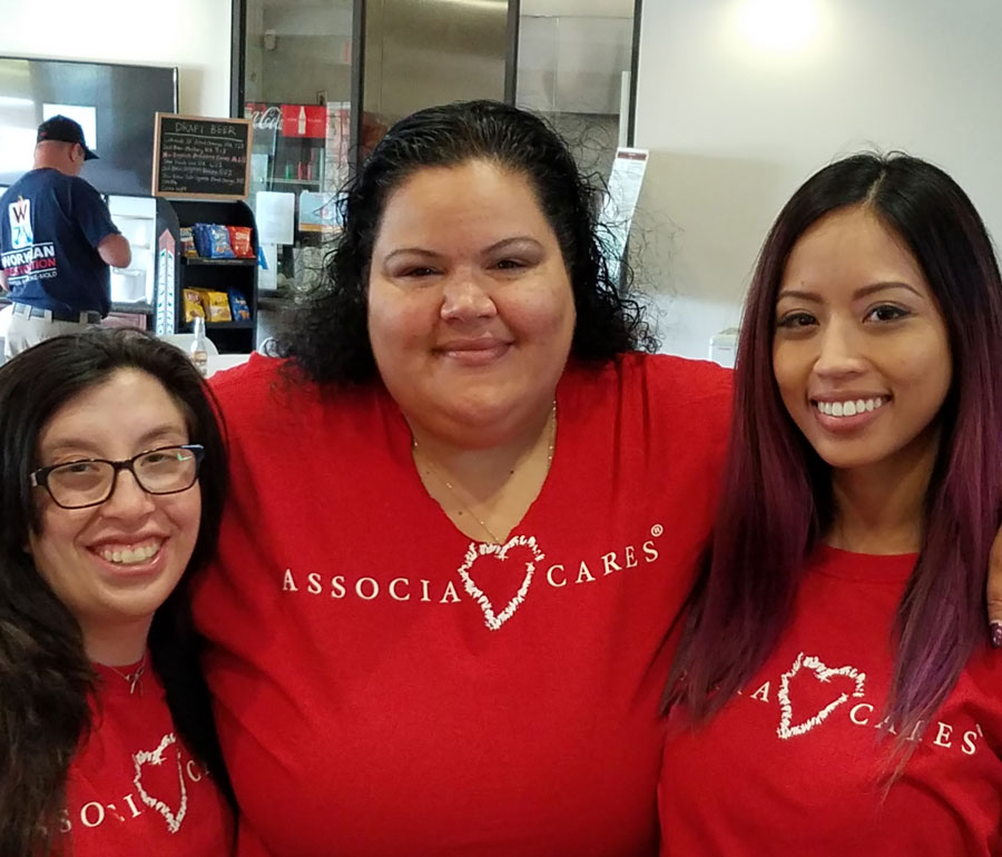 An image of 3 women with their arms around each others shoulders. They are smiling and wearing red Associa Cares shirts