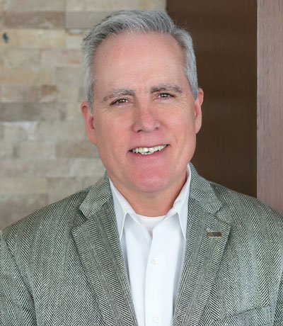 Headshot of Jeff Gourlie, a gray haired man with brown eyes, wearing a gray suit jacket on top of a white shirt.