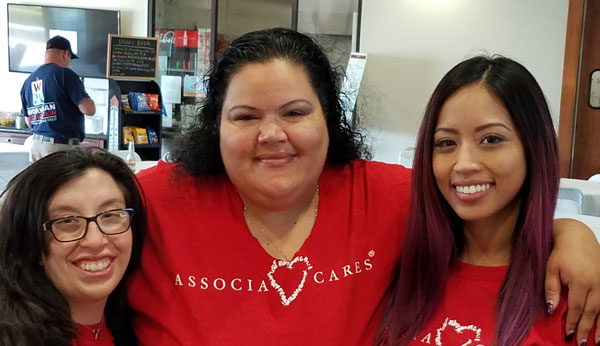An image of 3 women with their arms around each others shoulders. They are smiling and wearing red Associa Cares shirts